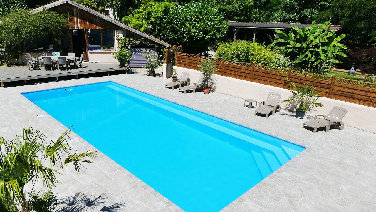 skimmer swimming pool with stone deck and landscaping